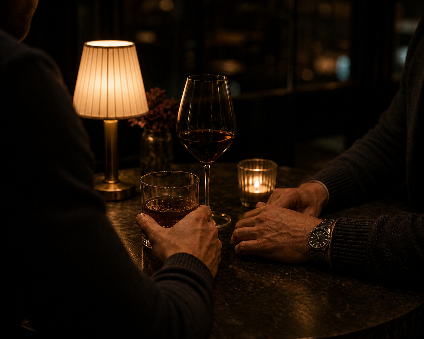 Two men's hands at a candlelit table with drinks